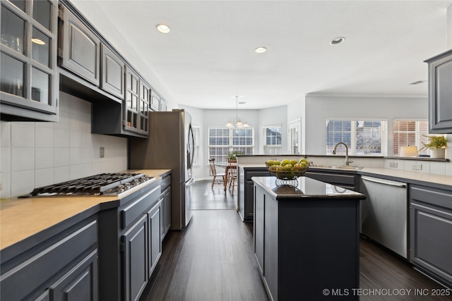 kitchen with sink, dark hardwood / wood-style flooring, decorative backsplash, a center island, and stainless steel appliances