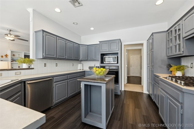 kitchen featuring stainless steel appliances, gray cabinetry, backsplash, and dark hardwood / wood-style flooring