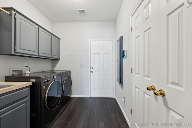 clothes washing area featuring cabinets, dark hardwood / wood-style floors, and washing machine and clothes dryer