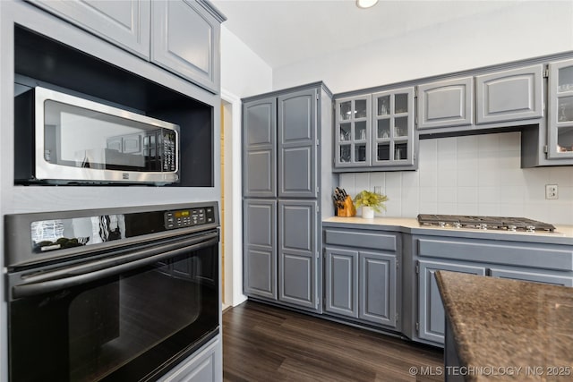 kitchen featuring stainless steel appliances, gray cabinets, backsplash, and dark hardwood / wood-style floors