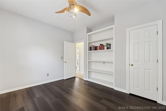 spare room featuring dark hardwood / wood-style floors, built in features, and ceiling fan