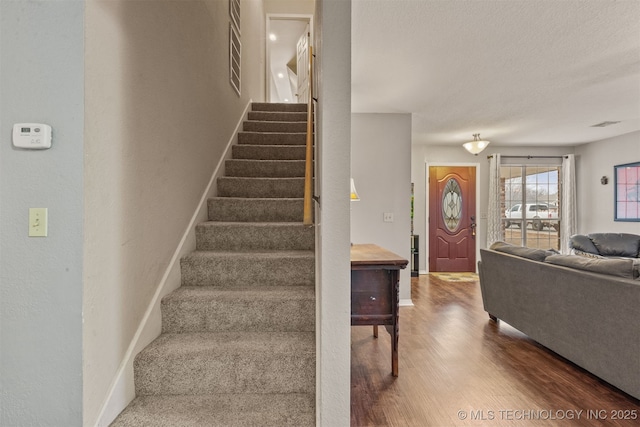 stairs featuring wood-type flooring and a textured ceiling