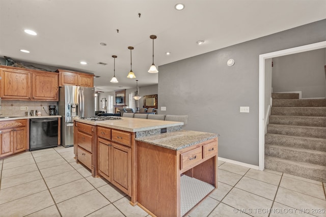 kitchen featuring pendant lighting, light tile patterned floors, stainless steel appliances, a kitchen island, and decorative backsplash