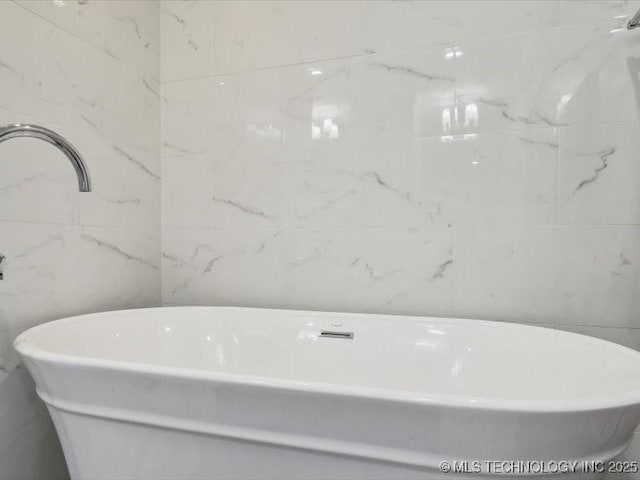 bathroom with tile walls and a bath