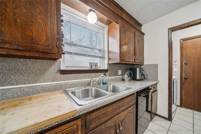 kitchen with sink, a textured ceiling, light tile patterned floors, black dishwasher, and backsplash