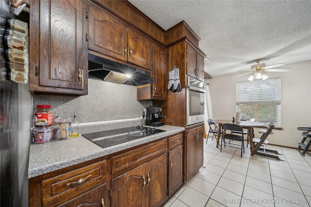 kitchen with light tile patterned flooring, black stovetop, tasteful backsplash, stainless steel oven, and a textured ceiling