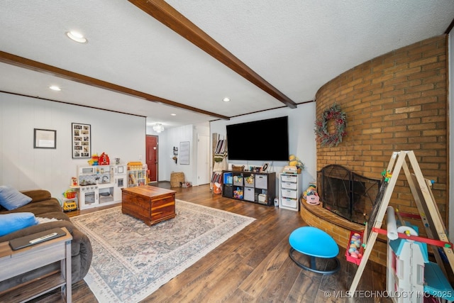 living room with beam ceiling, a fireplace, dark hardwood / wood-style floors, and a textured ceiling