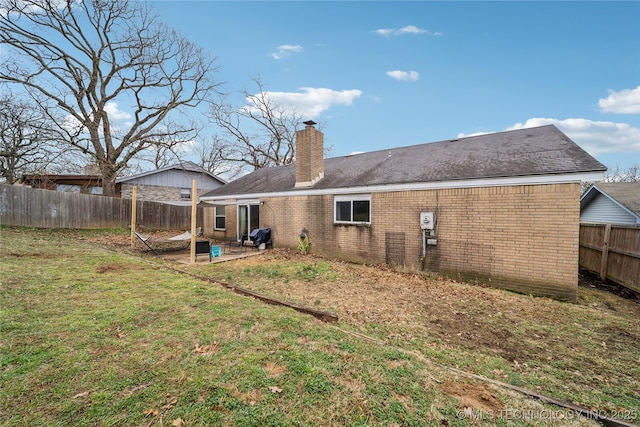 rear view of house with a patio and a lawn