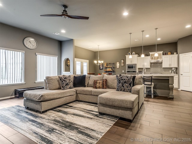 living room featuring ceiling fan with notable chandelier