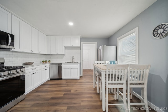 kitchen with sink, white cabinetry, appliances with stainless steel finishes, dark hardwood / wood-style flooring, and backsplash