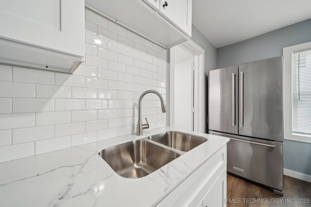 kitchen with sink, dark wood-type flooring, white cabinetry, light stone counters, and high quality fridge