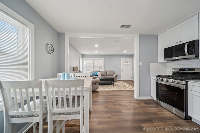 kitchen with tasteful backsplash, appliances with stainless steel finishes, dark hardwood / wood-style floors, and white cabinets