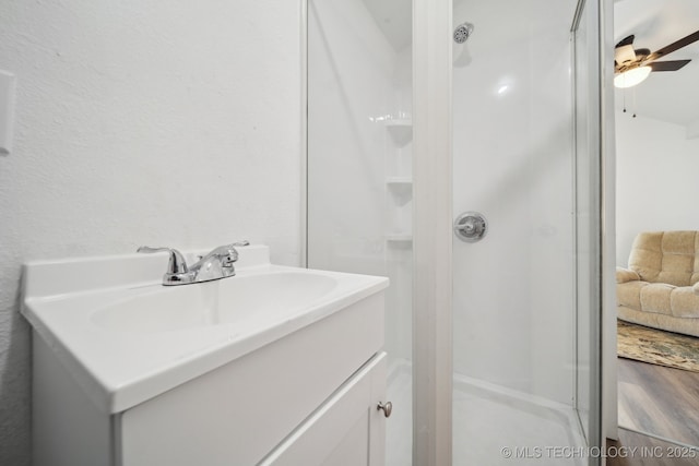 bathroom featuring walk in shower, ceiling fan, and vanity