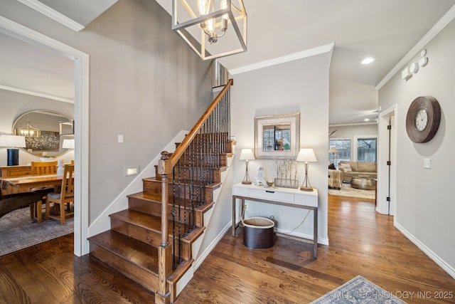 stairway with hardwood / wood-style flooring, crown molding, and a chandelier