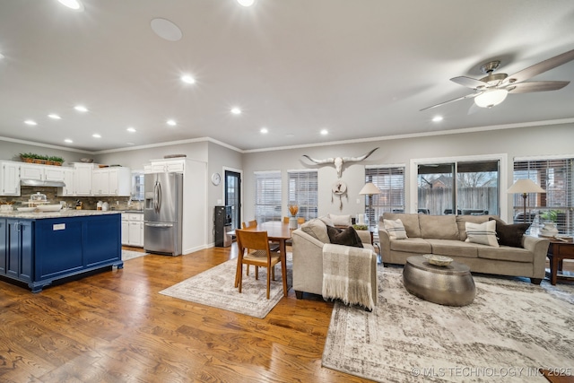 living room with hardwood / wood-style flooring, ornamental molding, and a healthy amount of sunlight