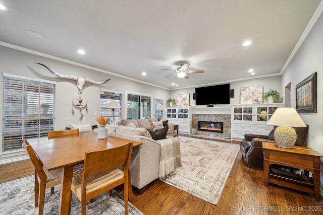 living room featuring ceiling fan, ornamental molding, a fireplace, and hardwood / wood-style floors