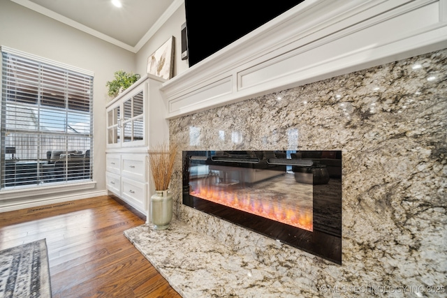 interior details featuring hardwood / wood-style flooring, ornamental molding, and a high end fireplace