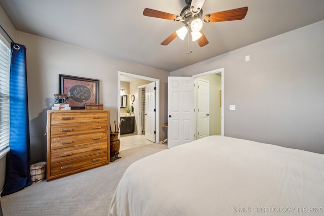 bedroom featuring ceiling fan, light colored carpet, and connected bathroom