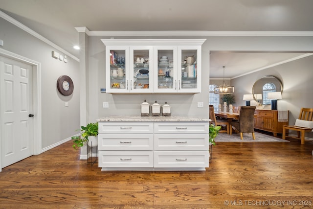 interior space with dark wood-type flooring, a notable chandelier, light stone countertops, and white cabinets