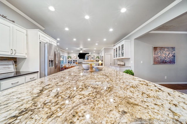 kitchen with white cabinets, stainless steel fridge, dark stone counters, ceiling fan, and crown molding