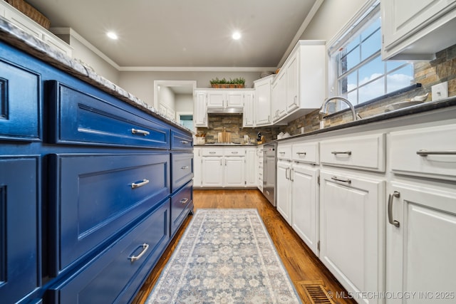 kitchen with dishwasher, white cabinetry, ornamental molding, blue cabinets, and decorative backsplash