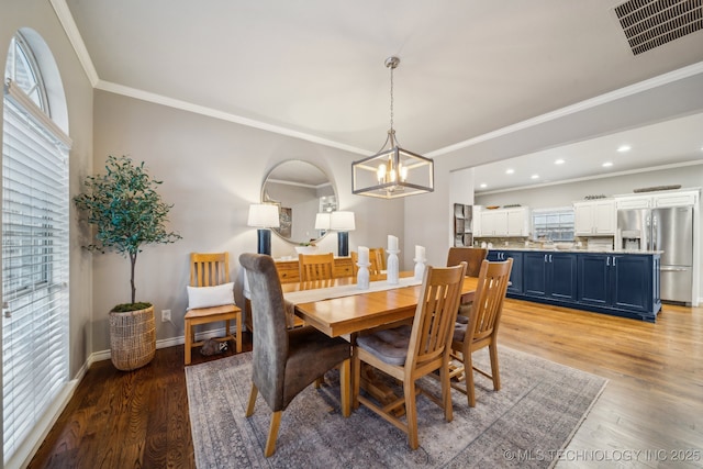 dining space featuring crown molding, light hardwood / wood-style floors, and a chandelier