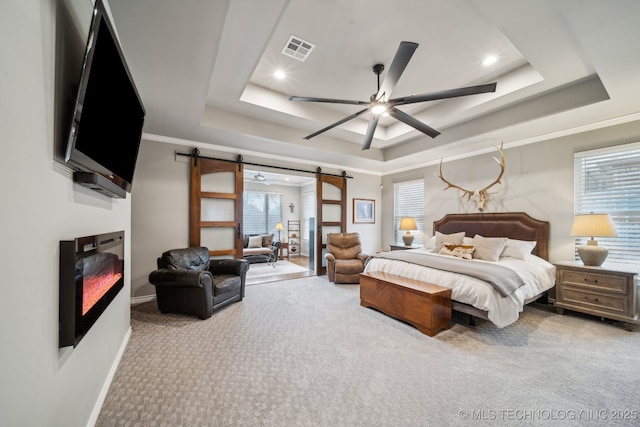 bedroom featuring crown molding, a barn door, a raised ceiling, and carpet