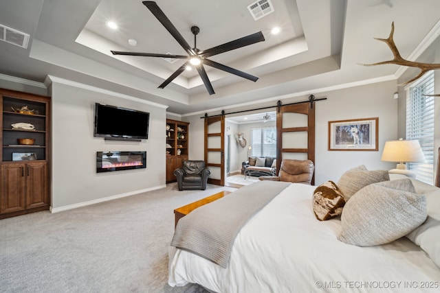 carpeted bedroom with crown molding, a tray ceiling, a barn door, and ceiling fan