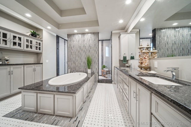 bathroom with a raised ceiling, vanity, and separate shower and tub