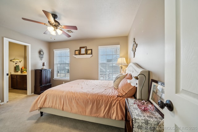 bedroom with ensuite bath, light colored carpet, ceiling fan, and a textured ceiling