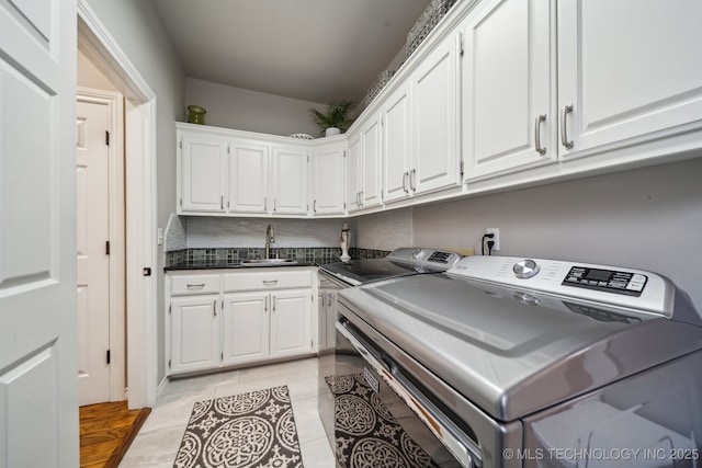 laundry room featuring sink, light tile patterned floors, washing machine and dryer, and cabinets