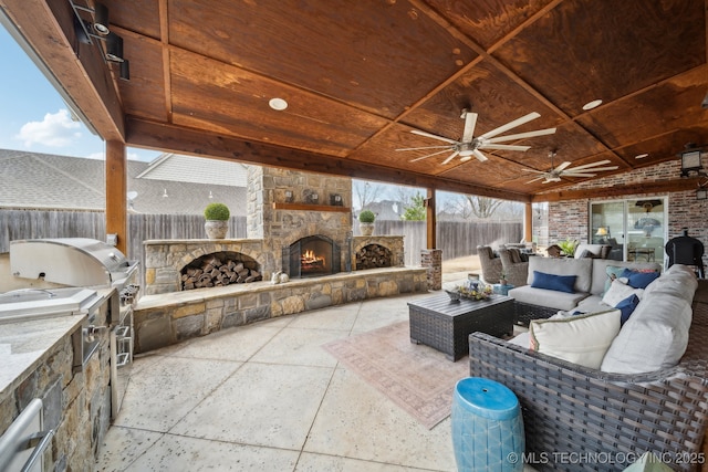 view of patio featuring an outdoor living space with a fireplace, ceiling fan, and exterior kitchen