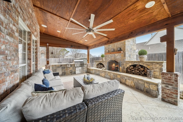 view of patio featuring area for grilling, ceiling fan, an outdoor stone fireplace, and an outdoor kitchen