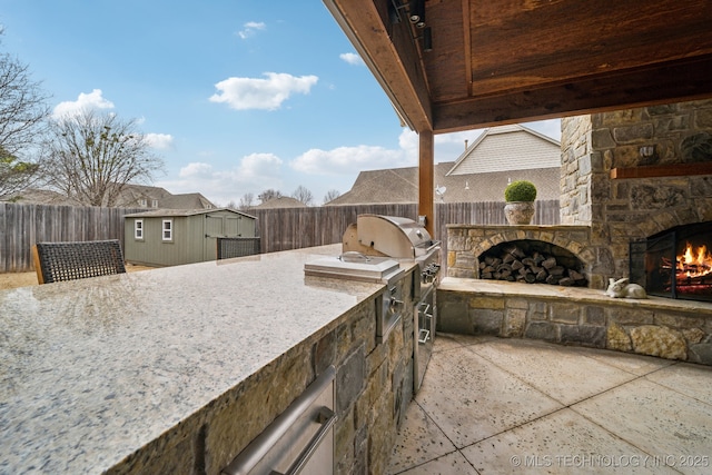 view of patio / terrace with grilling area, an outdoor structure, area for grilling, and an outdoor stone fireplace