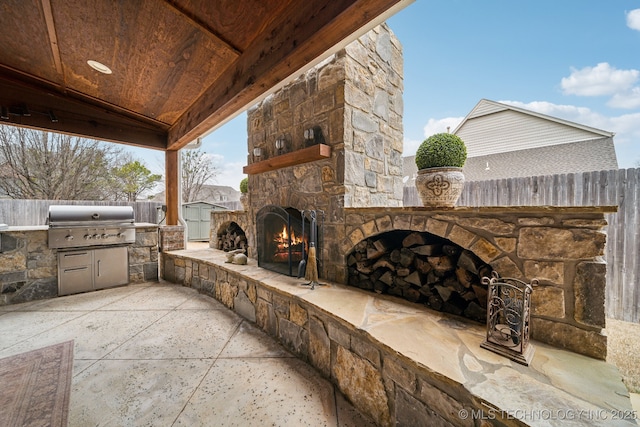 view of patio with a grill, an outdoor stone fireplace, and an outdoor kitchen