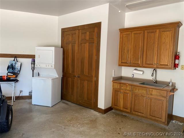 clothes washing area featuring stacked washer / drying machine and sink