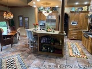 kitchen featuring a kitchen bar, ornate columns, decorative light fixtures, a center island, and a notable chandelier