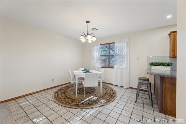 dining room with light tile patterned flooring and a chandelier