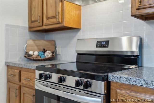 kitchen with electric stove, light stone countertops, and tasteful backsplash