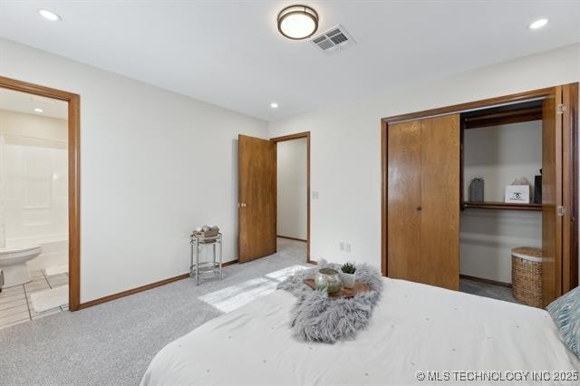 bedroom featuring light colored carpet, ensuite bath, and a closet