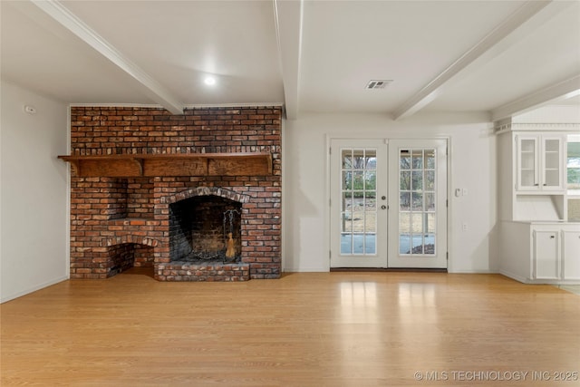 unfurnished living room with a fireplace, french doors, beamed ceiling, and light wood-type flooring