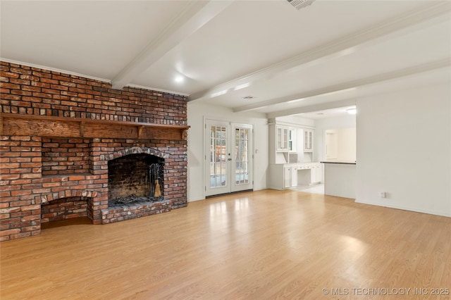 unfurnished living room featuring beamed ceiling, a brick fireplace, light hardwood / wood-style flooring, and french doors