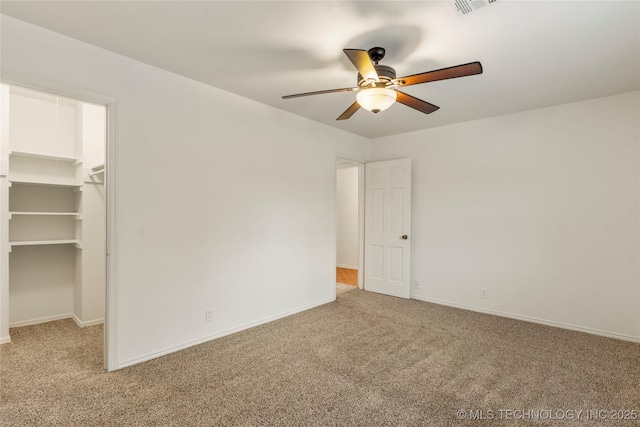 unfurnished bedroom with a spacious closet, light carpet, ceiling fan, and a closet