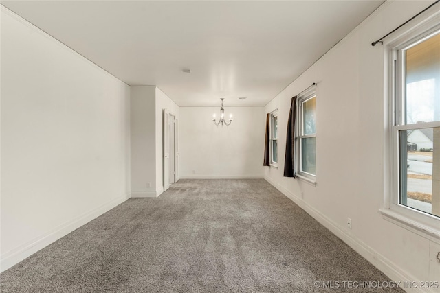 empty room featuring carpet flooring and a notable chandelier