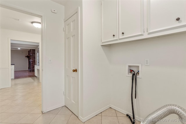 clothes washing area with light tile patterned floors, hookup for a washing machine, and cabinets