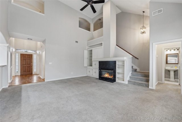 unfurnished living room featuring sink, high vaulted ceiling, a fireplace, ceiling fan with notable chandelier, and carpet