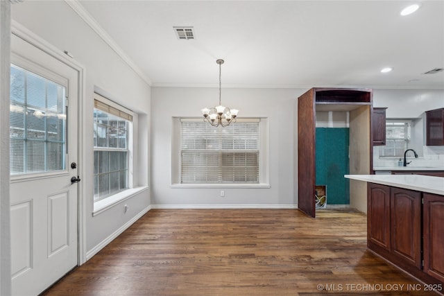 dining space with a healthy amount of sunlight, dark hardwood / wood-style flooring, a chandelier, and sink