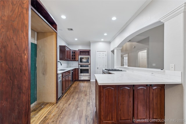 kitchen featuring ornamental molding, appliances with stainless steel finishes, kitchen peninsula, and sink