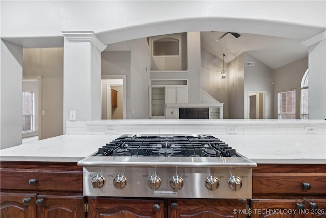 kitchen featuring ornate columns, vaulted ceiling, stainless steel gas cooktop, and dark brown cabinetry