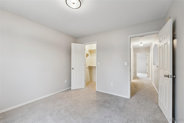 unfurnished bedroom with light carpet, a spacious closet, and a closet